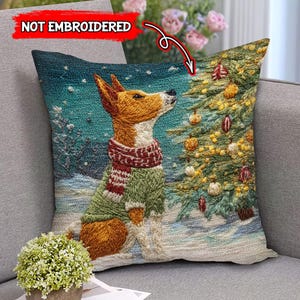 May include: Decorative throw pillow featuring a dog in a green sweater and red scarf, gazing at a Christmas tree. The pillow has a winter scene with snow and a teal background. The text "NOT EMBROIDERED" is visible.