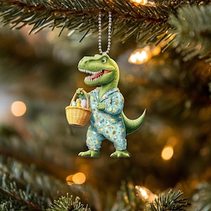 May include: A green dinosaur wearing blue pajamas with a basket of colorful Easter eggs. The dinosaur is holding the basket in its right hand and is looking to the right. The dinosaur is a Christmas ornament.