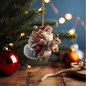 May include: A festive Christmas tree decoration depicting Santa Claus on a squirrel. Santa wears a red suit and has a white beard, carrying a sack of presents. The squirrel is brown and grey. The ornament hangs from a gold string.