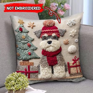 May include: A square cushion with a Schnauzer dog design wearing a red hat and scarf. The cushion features a Christmas tree and presents. The background is beige with snowflake and pom-pom accents. The text "NOT EMBROIDERED" is visible.