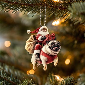May include: A Christmas ornament featuring Santa Claus riding a pug. Santa is wearing a red suit with white trim and a white beard. The pug is wearing a red and white suit. The ornament is hanging from a silver chain.