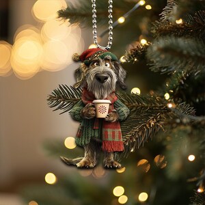Könnte beinhalten: Ein brauner und grauer Hund, der einen roten und grünen Schal und eine Weihnachtsmütze trägt, hält eine Papptasse Kaffee. Der Hund hängt an einer silbernen Kette.