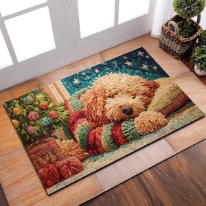 May include: A rectangular doormat featuring a sleeping dog with light brown fur, wearing a red, green, and white striped sweater. The mat has a Christmas tree and a starry night sky design. The mat is placed on a wooden floor.
