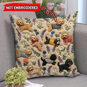 May include: Square beige throw pillow featuring multiple dog illustrations wearing sweaters and bandanas. The pillow has a floral pattern with lavender, daisies, and roses. The text "NOT EMBROIDERED" is in the upper left corner.