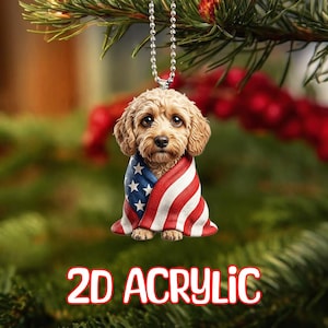 Puede incluir: Adorno acrílico 2D con un perro marrón envuelto en una bandera estadounidense. El perro tiene una expresión triste. El adorno cuelga de una cadena plateada. Las palabras "2D ACRYLIC" están en rojo y blanco en la parte inferior.