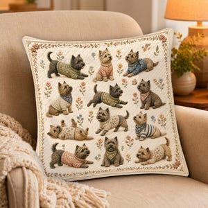 May include: A square throw pillow featuring a quilted cream-coloured fabric decorated with a repeating pattern of small terrier dogs wearing various sweaters and bandanas, interspersed with delicate embroidered floral motifs and a decorative border.