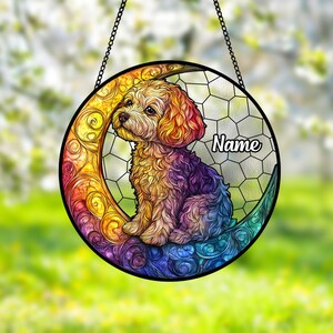 May include: A round, stained-glass dog ornament with a rainbow-colored crescent moon design. The dog is depicted with a fluffy coat in shades of gold, purple, and blue. The word "Name" is written on the right side of the ornament.