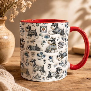 Könnte beinhalten: Ein weißer Keramikbecher mit leuchtend rotem Innenraum und Henkel, verziert mit einem wiederkehrenden Muster aus Schnauzer-Hunden in gemusterten Pullovern, durchsetzt mit blauen Blumenmotiven, Libellen und kleinen Herzsymbolen.