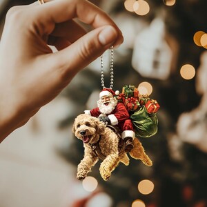 May include: A Christmas ornament featuring Santa Claus riding a brown dog, carrying a bag of presents. The ornament is hanging from a silver chain.