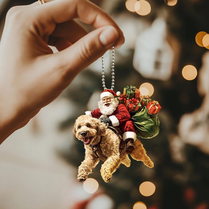 May include: A Christmas ornament featuring Santa Claus riding a brown dog, carrying a bag of presents. The ornament is hanging from a silver chain.