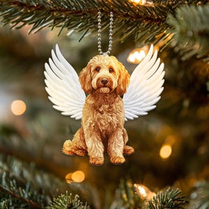 Può includere: Un cane marrone e bianco con ali d'angelo, un ornamento natalizio.