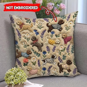 May include: Beige square throw pillow with a repeating pattern of various dog breeds wearing sweaters and bandanas, amidst embroidered flowers and lavender sprigs. The text "NOT EMBROIDERED" is in the upper left corner.