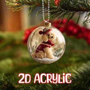May include: A clear glass Christmas ornament with a small poodle figurine inside. The poodle wears a red and white sweater, hat, and scarf. The ornament hangs from a silver chain and has the text "2D ACRYLIC" in red and white.