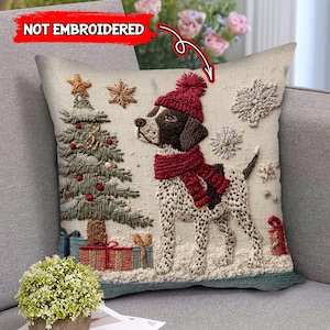 Könnte beinhalten: Dekoratives Weihnachtskissen mit einem Hund, der eine rote Mütze und einen Schal trägt, neben einem geschmückten Weihnachtsbaum und Geschenken. Das Kissen hat ein strukturiertes, gesticktes Aussehen mit Schneeflocken- und Sternakzenten. Der Text "NOT EMBROIDERED" ist sichtbar.
