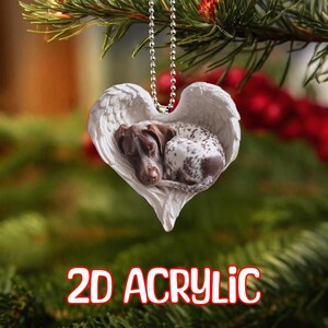 Könnte beinhalten: Ein herzförmiger 2D-Acrylschmuck mit einem schlafenden Hund in Engelsflügeln. Der Hund hat braunes und weiß geflecktes Fell. Der Schmuck hängt an einer silbernen Perlenkette. Der Text "2D ACRYLIC" befindet sich unten.