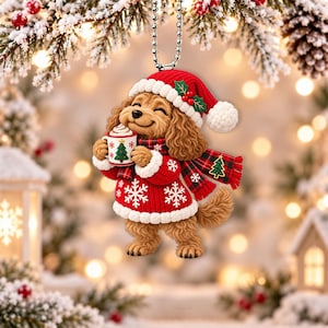 Könnte beinhalten: Ein hängender Weihnachtsbaumschmuck in Form eines braunen, lockigen Hundes, der eine rote Strickmütze mit weißem Rand, einen roten Pullover mit weißen Schneeflockenmustern und einen rot-grün karierten Schal trägt und eine weiße Tasse hält.
