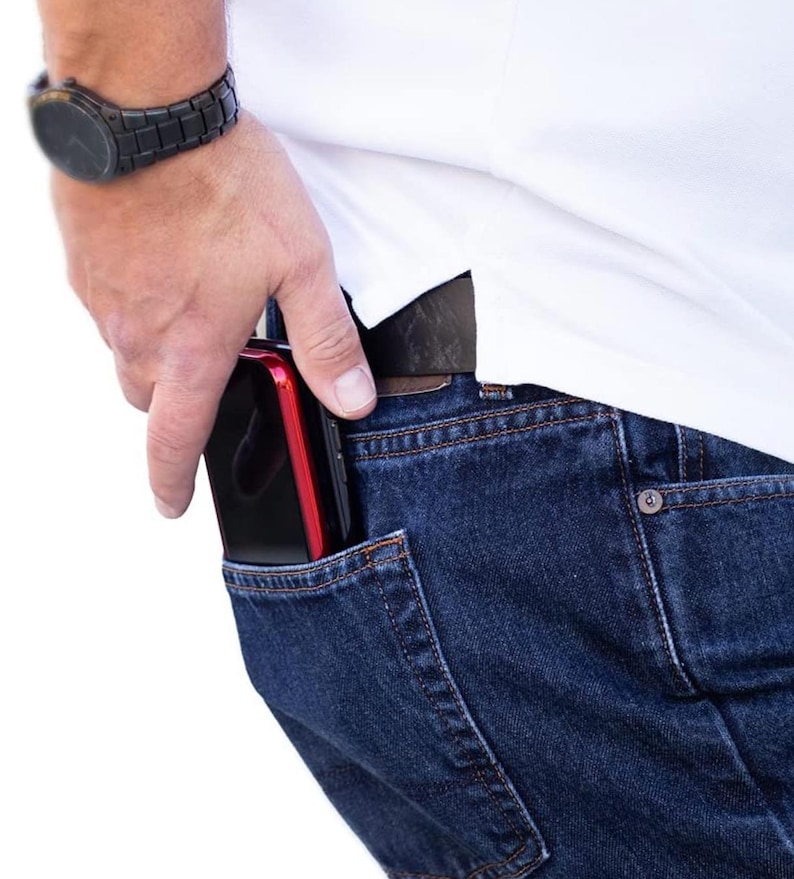 May include: A person wearing blue jeans with a black and red phone in the back pocket.