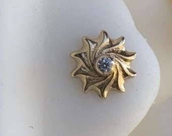 May include: A gold-toned nose piercing with a spiral design and a small clear gemstone in the center.