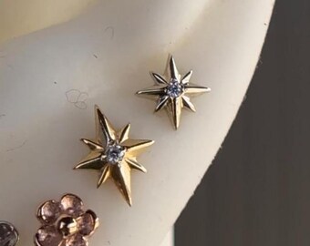 May include: Two gold star-shaped earrings with a small clear diamond in the center of each star.