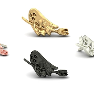 May include: Four ghost pins in various colours: rose gold, gold, silver, and black. Each pin depicts a ghost with three eye holes, holding a broom. The pins are presented against a white backdrop.