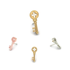 May include: Three key-shaped earrings in gold, silver, and rose gold. The earrings are all the same design, with a round keyhole and a small keyhole on the side.