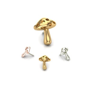 May include: Four mushroom-shaped stud earrings in gold, rose gold, and silver tones. The largest earring is gold and stands upright, while the others are arranged around it. The earrings have a whimsical, nature-inspired design.