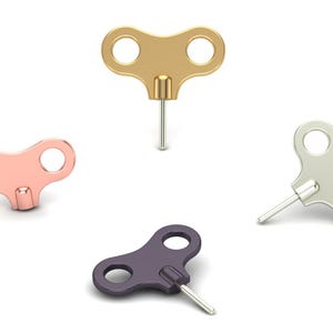 May include: Four wind-up keys in gold, rose gold, silver, and purple. Each key has a circular handle with two holes and a metal pin. The keys are arranged on a white background.