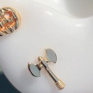 May include: Gold-toned axe charm with a detailed handle. The axe is a popular Halloween theme.