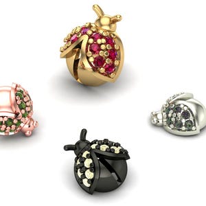 May include: Four ladybug-shaped charms in gold, rose gold, silver, and black. Each charm is encrusted with gemstones in various colors, including red, green, and black. The charms are displayed against a white background.