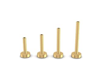 May include: Four gold-colored metal body jewelry posts of varying lengths. The posts are cylindrical with a flat, round base.