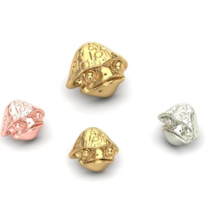 May include: Four mushroom-shaped charms in gold, silver, and rose gold. Each charm features a detailed design with a textured surface.
