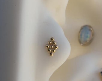 May include: A gold nose ring with a diamond-shaped cluster of small beads.