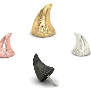 May include: Four decorative horn-shaped objects in gold, rose gold, silver, and black. The black horn has a post attached. The horns have a textured surface and are displayed against a white background. These are likely jewelry or craft supplies.