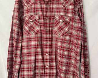 May include: A red and beige plaid long-sleeved shirt with snap closures and two chest pockets. The shirt has a western style with a pointed collar and the brand name "ROUGH STOCK" on the label.