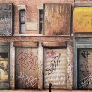 May include: An urban street scene featuring a brick building with weathered metal storefronts and roll-up doors. Graffiti art adorns the doors, adding a gritty, artistic element. The building's facade includes windows and aged signage.
