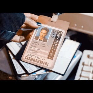 May include: A clear plastic ID badge with the name "METADORTEX" printed vertically. The badge features a photo of a young man and reads "ANDERSON, THOMAS A. Junior Programmer" with an issue date of "28 May 1996".