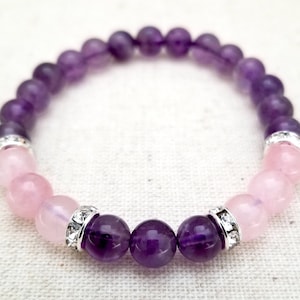 May include: A purple and pink gemstone bracelet with silver accents. The bracelet is made with amethyst and rose quartz beads.