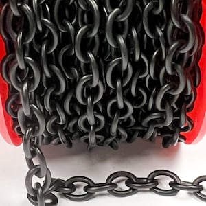 May include: A close-up of a black chain coiled on a red spool. The chain is made of metal and has a matte finish.