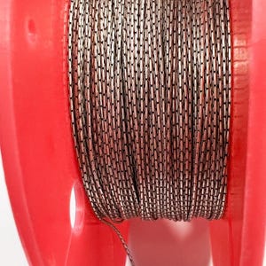 May include: A spool of silver-colored chain with a red plastic container. The chain is made of small, oval-shaped links.