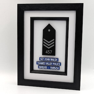 May include: Framed police sergeant's badge in black and white, featuring the text "SGT JOHN WALSH", "THAMES VALLEY POLICE", and dates "20/05/05 - 19/05/24". The badge is black with silver stripes and the number "457".