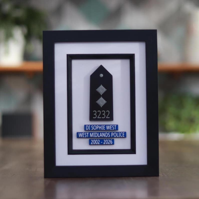 May include: Framed black plaque featuring a police badge with the number 3232 and the name DI Sophie West. The text "WEST MIDLANDS POLICE 2002-2026" is also displayed. The plaque is set against a white background within a black frame.
