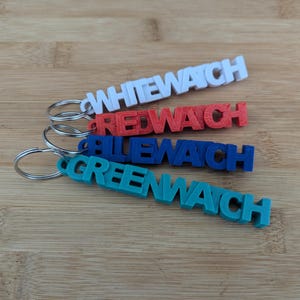 Può includere: Quattro portachiavi con le parole "Whitewatch", "Redwatch", "Bluewatch" e "Greenwatch" stampate su di essi. I portachiavi sono in plastica e sono di colore bianco, rosso, blu e verde.
