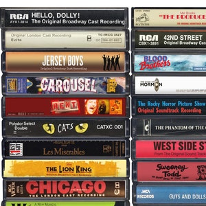 May include: A collection of vintage cassette tapes featuring Broadway show soundtracks. The tapes are arranged vertically in two columns. The titles include "Hello, Dolly!", "Evita", "Jersey Boys", "Carousel", "Rent", "Cats", "Les Mis&eacute;rables", "The Lion King", "Chicago", "The Producers", "42nd Street", "Blood Brothers", "The Book of Mormon", "The Rocky Horror Picture Show", "The Phantom of the Opera", "West Side Story", "Sweeney Todd", and "Guys and Dolls".