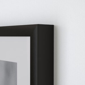 May include: A black picture frame with a white mat. The frame is made of wood and has a simple, modern design.