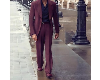 May include: A burgundy suit with a matching jacket and trousers. The jacket has a notched lapel and a two-button closure. The trousers are straight-legged. The suit is paired with a navy blue shirt and burgundy shoes. The image is taken outdoors.