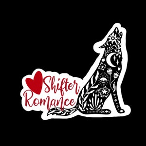 May include: Black and white illustration of a wolf howling at the moon. The wolf is decorated with floral patterns and the text "Shifter Romance" is written in red cursive. A red heart is to the left of the text.