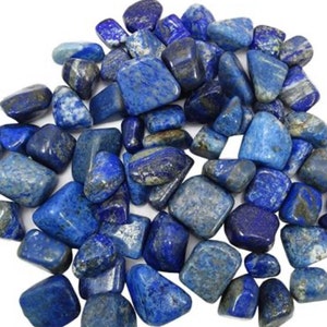 Peut inclure: Une collection de pierres de lapis-lazuli roulées. Les pierres sont d'un bleu profond avec des veines blanches qui les traversent. Elles sont lisses et polies, et ont une forme naturelle irrégulière.
