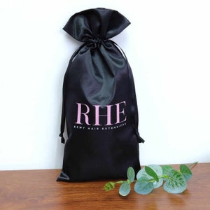 May include: A black satin drawstring bag with the text "RHE Remy Hair Extensions" printed in pink letters.