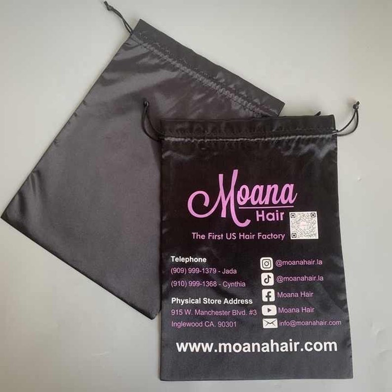 May include: Black satin drawstring bag with the text "Moana Hair The First US Hair Factory" printed in pink. The bag also includes contact information, including a phone number, email address, and social media handles.