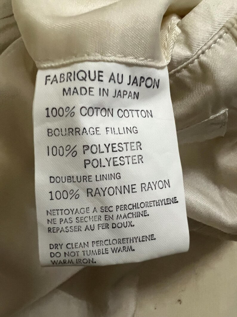 May include: A label with French and English text, including "FABRIQUE AU JAPON MADE IN JAPAN", "100% COTON COTTON", "100% POLYESTER", and "100% RAYONNE RAYON". The label also features care instructions.